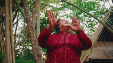 Sabahları tropikal bahçede dans eden kırmızı elbiseli kadın.