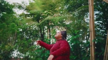 Bir gelinin orman ortamında özgürce dans edişinin sanatsal görüntüleri, kırmızı elbisesinin ve uzun saçlarının yeşil gölgeliğe doğru hareketini yakalıyor..