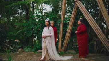 Geleneksel kıyafetli üç kadın sabah boyunca bambu yapılarıyla ormanda sohbet ediyorlar.