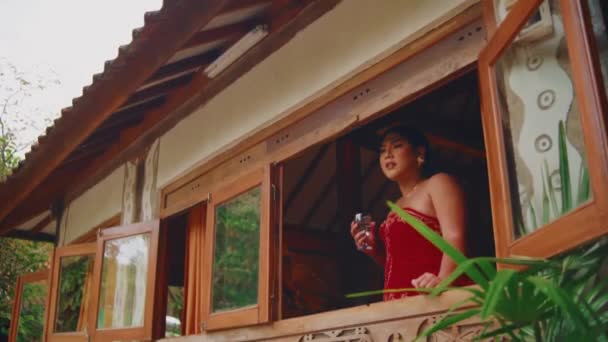 Woman Red Dress Enjoying View Rustic Cabin Window Surrounded Nature — 비디오