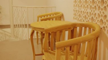 İki ahşap sandalye ve küçük yuvarlak bir masa dekoratif duvar desenli kapalı bir ortamda..