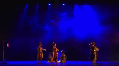 Dansçıların siluetleri gece boyunca süren çağdaş bir performans sırasında dramatik mavi ışıkla sahnede.