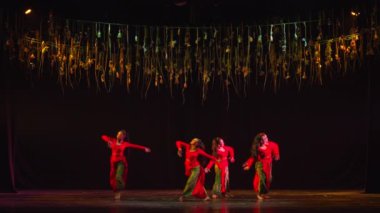 Sahne ışıkları tarafından aydınlatılan karanlık bir arka plan karşısında dans eden dansçılarla çağdaş dans performansı..