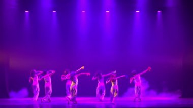 Gece boyunca mor ışıklı ve dumanlı dansçıların siluetleri sahnede.