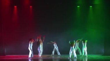 Dansçılar, gece boyunca süren çağdaş bir gösteri sırasında dramatik ışıklandırmayla sahnede.