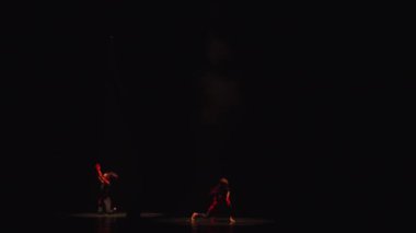 Karanlık bir sahnede siluetli dansçılar, gece boyunca dramatik bir çağdaş performans yakaladılar.