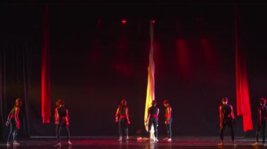 Sahnedeki siluetli dansçılar gece boyunca süren çağdaş bir performans sırasında dramatik kırmızı ve mor ışıkla