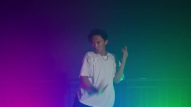 Beyaz gömlekli bir kişi, bulanık hareket etkisine sahip renkli ışıkların altında dramatik bir şekilde poz verir..