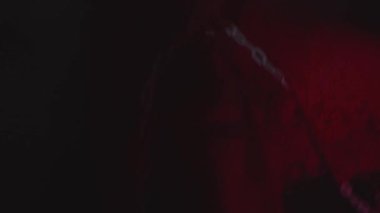 Kırmızı ışıklı loş bir odada bulanık bir insan görüntüsü. Kırmızı bir kıyafet giyiyor gibi görünüyor ve biraz bulanık..