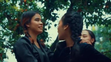 Bir grup insan, meyveli bir ağacın altında neşeyle dans ediyor..