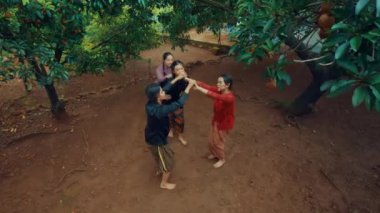 Geleneksel giyinmiş bir grup kadın kırsal alanda meyve ağaçlarının altında dans ediyorlar..