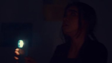 Uzun saçlı bir insan loş bir odaya bakıyor ve gizemli bir atmosfer yaratıyor..