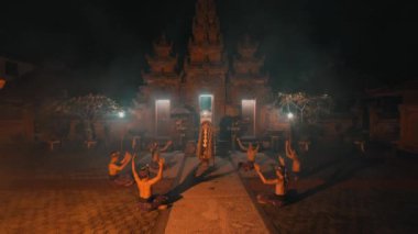 Karmaşık bir şekilde tasarlanmış bir tapınağın önünde geleneksel bir Bali dansı gösterisi. Dansçılar geleneksel kıyafetler giyerler ve hafif ışıkla aydınlatılarak mistik bir atmosfer yaratırlar..