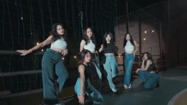 Altı genç kadından oluşan bir grup, geceleri spor sahasında rahat bir şekilde poz veriyorlar..