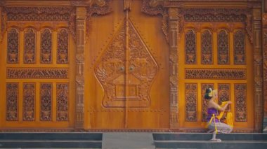 Geleneksel dans gösterisine hazırlanan iki kadının yakın çekimi. Bir kadın diğerinin süslü altın başlığını düzeltiyor. Makyaj ve mücevherleri var.. 