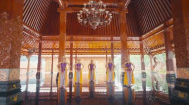 Süslü ahşap mimarisi olan geleneksel bir Bali pavyonu. Cilalı zemini yansıtan renkli kostümler içinde beş dansçı sıraya dizildi. İç kısımda karmaşık oymalar ve avize var. Huzurlu bir atmosfer yaratıyor..