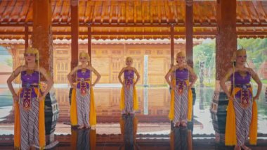 Renkli kostümlü dansçıların güzel tasarlanmış ahşap bir köşkte dans ettiği geleneksel bir dans gösterisi. Dansçılar zarif bir şekilde poz veriyor, kıyafetlerini ve etraflarındaki huzurlu çevreyi sergiliyorlar..