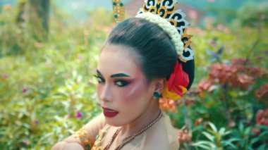 Kayalık arazinin yakınındaki çimenlerde çıplak ayakla yürüyen birinin yakın çekimi. Kişi renkli, desenli bir elbise giyiyor. Hareketle birlikte yavaşça akıyor.