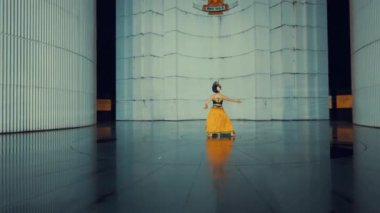 Geleneksel giyinmiş bir kadın, açık hava ortamında güven içinde poz verir. Karmaşık desenleri olan, taç ve kırmızı aksesuarlarla tamamlanmış güzel tasarlanmış siyah ve altın bir elbise giyiyor.