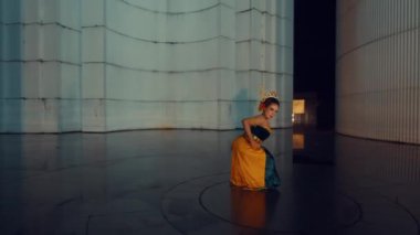 Kayalık arazinin yakınındaki çimenlerde çıplak ayakla yürüyen birinin yakın çekimi. Kişi renkli, desenli bir elbise giyiyor. Hareketle birlikte yavaşça akıyor.