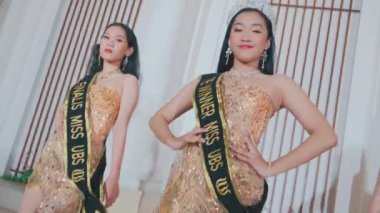 Taçlı şampiyon ve iki finalist sahne basamaklarında birlikte poz veriyorlar. Altın elbiselerini sergileyerek senkronize bir dönüş yapıyorlar..