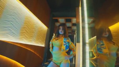 Modern bir iç koridorda yüksek enerjili bir pop dansı gösterisi. Dansçı zıplar ve hızlı hareket eder. Şık bir mekanda K-Pop 'un esinlendiği bir koreografiyi sergiler..