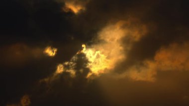 Karanlık bulutlarla dolu dramatik bir gökyüzü ve güneş ışınları yararak çarpıcı bir ışık ve gölge kontrastı oluşturuyor..