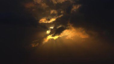 Kara bulutlar ve güneş ışınlarıyla dramatik gökyüzü karamsar bir atmosfer yaratıyor..