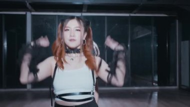 Modern bir stüdyo ortamında gösteri yapan bir grup dansçı. Şık, şık kıyafetler giyiyorlar, dinamik pozlar ve ifadeler sergiliyorlar. Arka planda büyük cam pencereler ve çarpıcı ışıklandırma yer alıyor, enerjik atmosferi artırıyor.