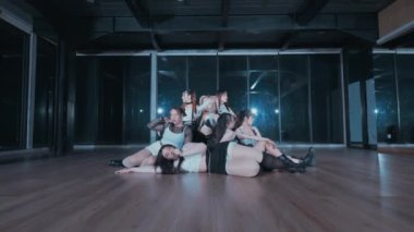 Bir grup dansçı loş bir stüdyoda dinamik ve etkileyici bir gösteri sergiliyorlar. Dansçılar çeşitli pozlarda, hareket ve takım çalışmasını vurguluyorlar..