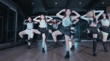 Büyük pencereli bir stüdyoda sekiz dansçıdan oluşan bir grup. Şık kıyafetler giyiyorlar, dinamik bir dans gösterisi sergiliyorlar. Işıklandırma dramatik, hareketlerini vurguluyor..