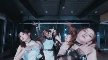 Bir grup dansçı stüdyoda senkronize bir gösteri yapıyor. Şık kıyafetler giyiyorlar ve dinamik hareketler sergiliyorlar. Atmosfer enerjik ve enerjik, çarpıcı ışıklandırmayla..