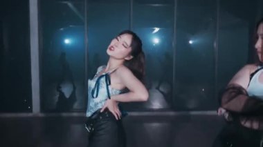 Modern bir stüdyo ortamında dört kadın dansçının olduğu dinamik bir dans gösterisi. Baş dansçı odak noktasında, dışavurumcu hareketler sergiliyor, diğerleri ise arka planda hafifçe bulanıklaşarak hareket duygusunu arttırıyor..