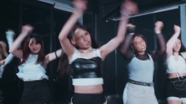 Büyük pencereli loş bir stüdyoda üç dansçı sahne alıyor. Şık kıyafetler giyiyorlar ve kareografilerini vurgulayarak dinamik pozlar veriyorlar..