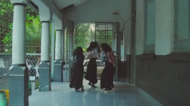 Okul üniformalı üç kişi koridorda kolonlarla yürüyor. Görüntü bulanık, hareket izlenimi veriyor..