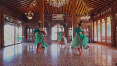 İçerde canlı bir geleneksel dans gösterisi gerçekleştiriliyor. Dansçılar renkli kostümler giyer, etekleri dalgalı ve karmaşık tasarımları vardır, kültürel mirası gözler önüne sererler.. 