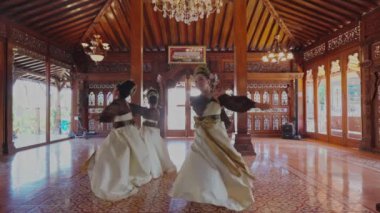 Geleneksel bir dans gösterisi. Zarif kostümlü dört dansçının karmaşık tasarımları var. Çok güzel dekore edilmiş ahşap bir salonda, süslü oymalar ve avizeler var..