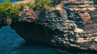Üzerinde yemyeşil yemyeşil bir su bulunan engebeli bir kaya oluşumu. Sahne doğanın güzelliğini yakalıyor, kayalık dokuyla canlı deniz arasındaki zıtlığı vurguluyor..