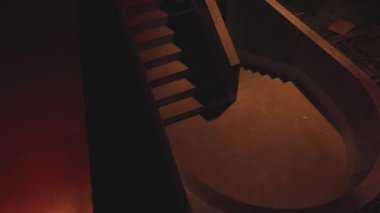 Pürüzsüz, kıvrımlı dizaynlı loş bir merdiven. Adımlar gölgeli ve karanlık ortama karışıp gizemli bir atmosfer yaratıyor..