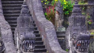 Ejderha benzeri heykeller ve gür yeşillik içeren karmaşık oyulmuş taş merdivenlerin yakın çekim görüntüsü. Basamaklar bir tapınağa ya da kutsal bir yere çıkıyor. Detaylı sanat eserleri ve canlı çiçekler sergileniyor..