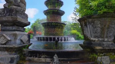 Yeşillik ve renkli çiçeklerle çevrili güzel katmanlı bir çeşme. Su fıskiyenin seviyesinden aşağı akarak sakin bir atmosfer yaratıyor..