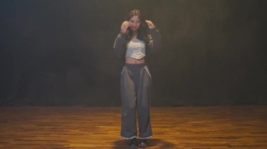 Duman efektleriyle loş bir stüdyoda dans eden bir dansçı. Dansçı günlük kıyafetler giyiyor, özgürlük ve ifade duygusu ile dinamik bir hareket sergiliyor..