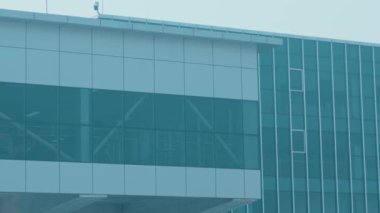 Önünde büyük cam pencereler ve bir otobüs olan modern bir bina. Mimaride cam ve metal elementlerin karışımından oluşan parlak, çağdaş bir tasarım yer almaktadır..