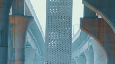Köprü yapısının modern mimari görüntüsü. Merkezi bir sütunda karmaşık desenler var. Yukarıdaki beton kirişler ve otoyollarla çevrili..