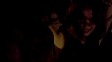 Terk edilmiş bir binada loş bir sahne, iki gölge figürün yer aldığı. Bir figür üzerinde bir çanta veya nesne asılı bir halat tutarken, diğer figür yakınlarda duruyor. Atmosfer gergin ve gizemli. 