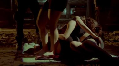 Loş ve terk edilmiş bir alanda duran bir grup insanın siluetleri. Atmosfer gölgelerle ve manzarayı aydınlatan bir ışık demeti ile ürkütücü. Rakamlar gizemli ve konumlandırılmış görünüyor. 