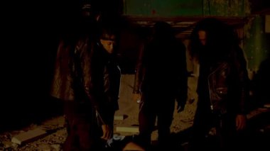 Loş ve terk edilmiş bir alanda duran bir grup insanın siluetleri. Atmosfer gölgelerle ve manzarayı aydınlatan bir ışık demeti ile ürkütücü. Rakamlar gizemli ve konumlandırılmış görünüyor. 