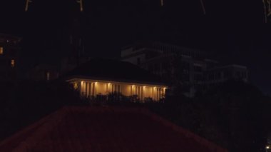 Geceleyin loş bir ara sokak, yıpranmış duvarlar ve manzarayı aydınlatan bir sokak lambası. Atmosfer sessiz ve tüyler ürpertici. Işığın yansıttığı gölgeler var. Uzakta birkaç park edilmiş araç görülüyor, konutlarla çevrili..