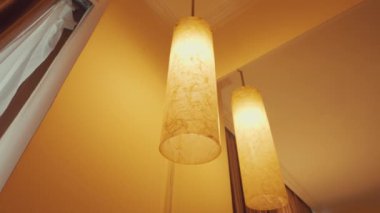 Geceleyin loş bir ara sokak, yıpranmış duvarlar ve manzarayı aydınlatan bir sokak lambası. Atmosfer sessiz ve tüyler ürpertici. Işığın yansıttığı gölgeler var. Uzakta birkaç park edilmiş araç görülüyor, konutlarla çevrili..