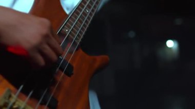 Arka planda bulanık bir gitar çalan birinin yakın çekimi. Kolunda karmaşık tasarımlar olan beyaz bir gömlek giyiyor..